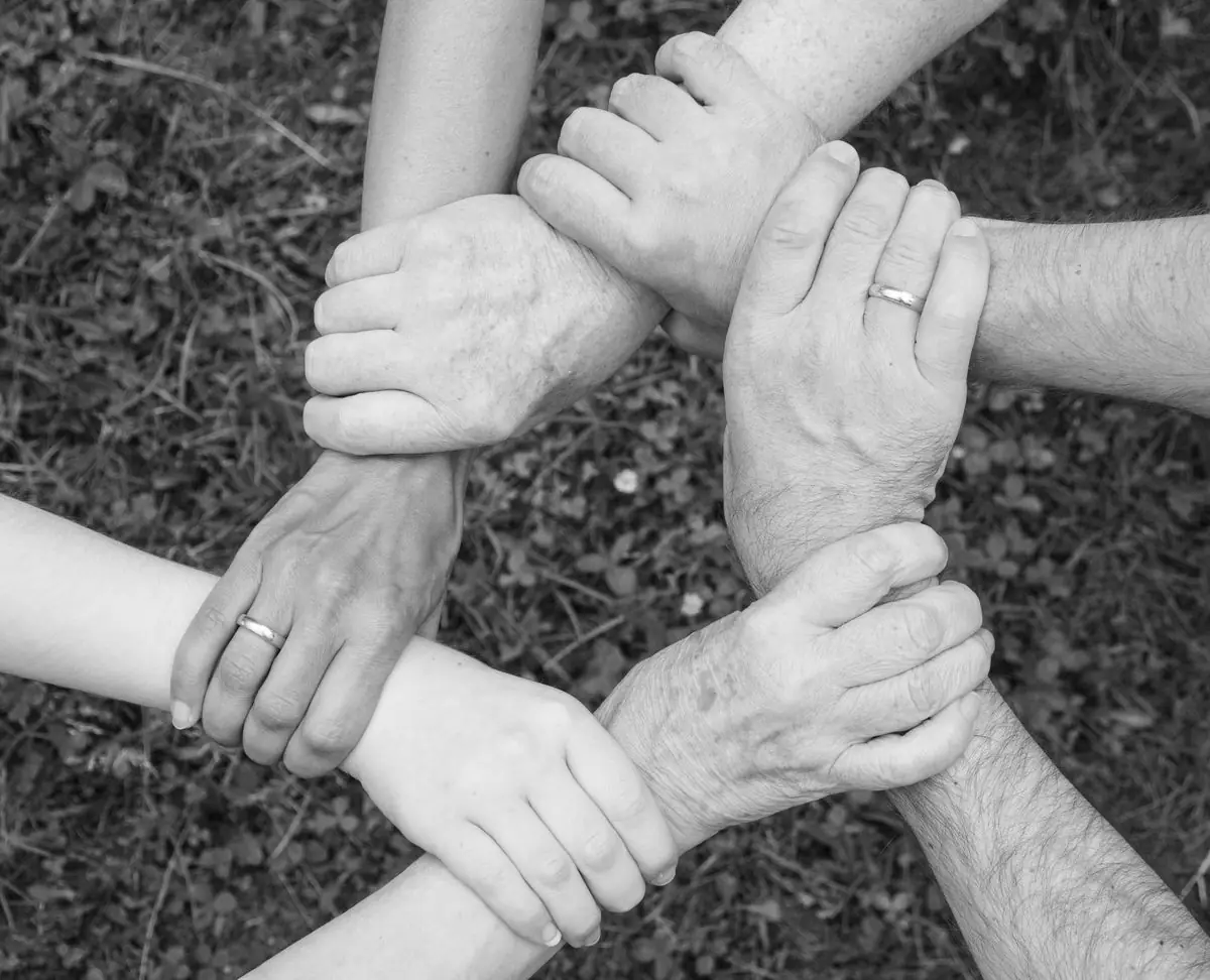 Varias manos de adultos entrelazadas formando un círculo